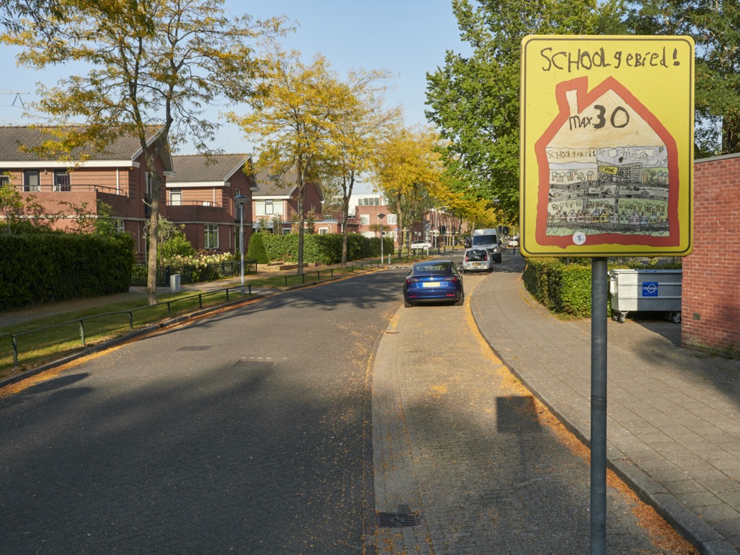 Foto van een waarschuwingsbordje in een woonwijk: schoolgebied