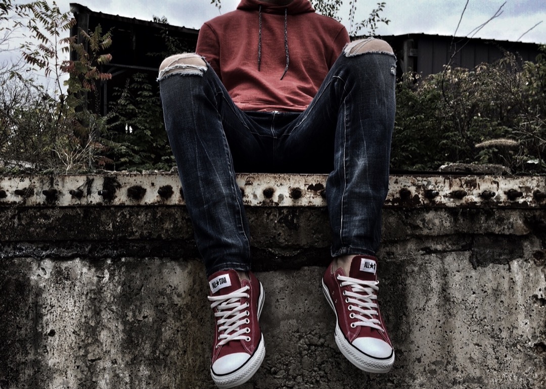 Foto van een jongere zittend op een muurtje