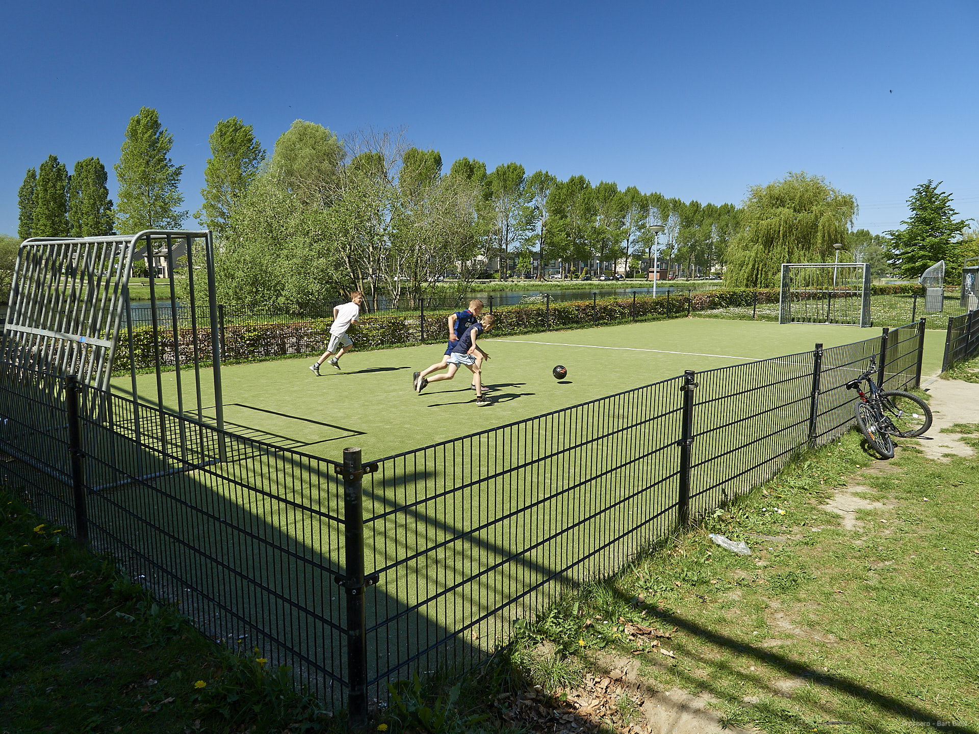 Afbeelding:Foto van voetbalveldje met spelende jongens