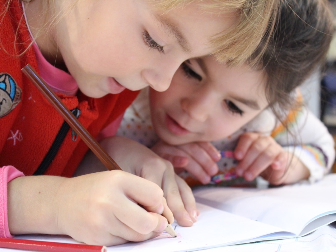 Twee meisjes tekenen in een schriftje